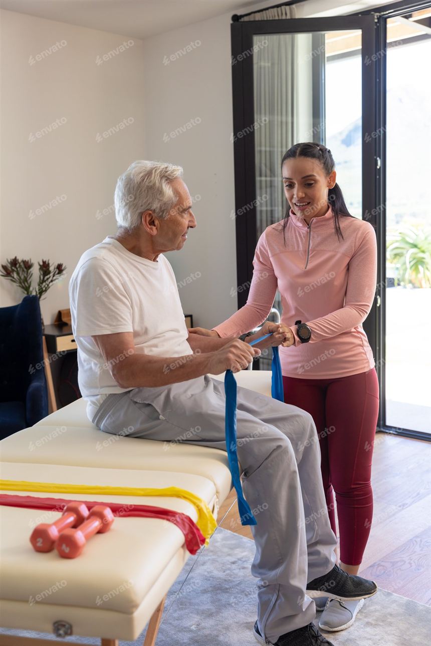 Physiotherapeutin hilft einem älteren Patienten beim Üben mit dem Widerstandsband zuhause