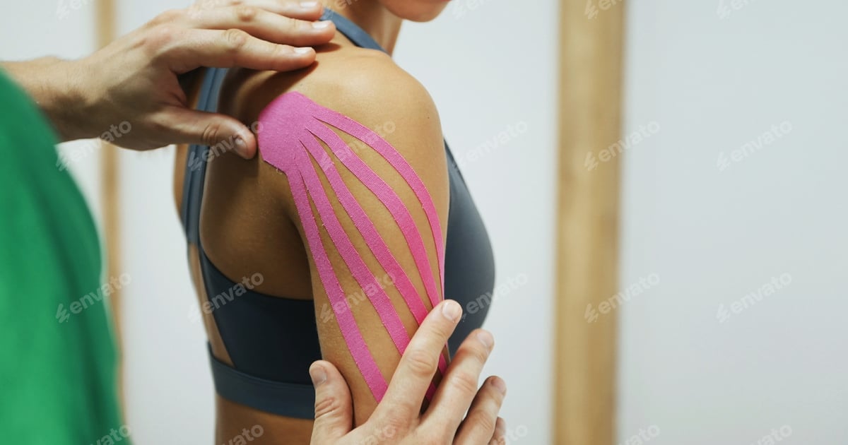 Physiotherapeut bringt ein elastisches kinesiologisches Tape auf der Schulter einer Patientin an