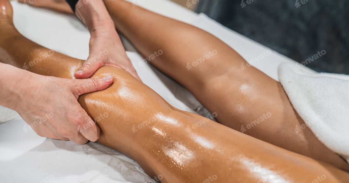 Physiotherapeutin führt eine manuelle Lymphdrainage am Bein einer Patientin durch