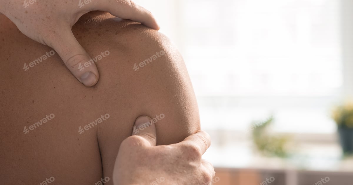Physiotherapeut mobilisiert das Schultergelenk einer Patientin bei einer manuellen Therapie zuhause