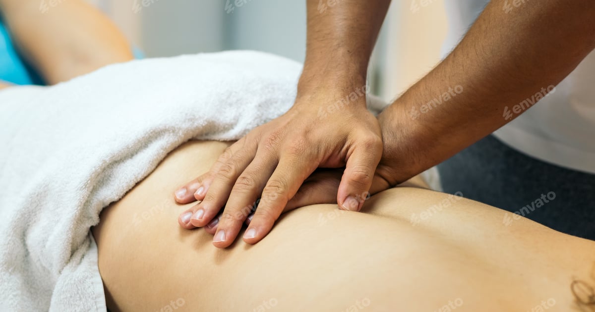 Therapeutin massiert den Rücken eines Patienten auf einer mobilen Massageliege